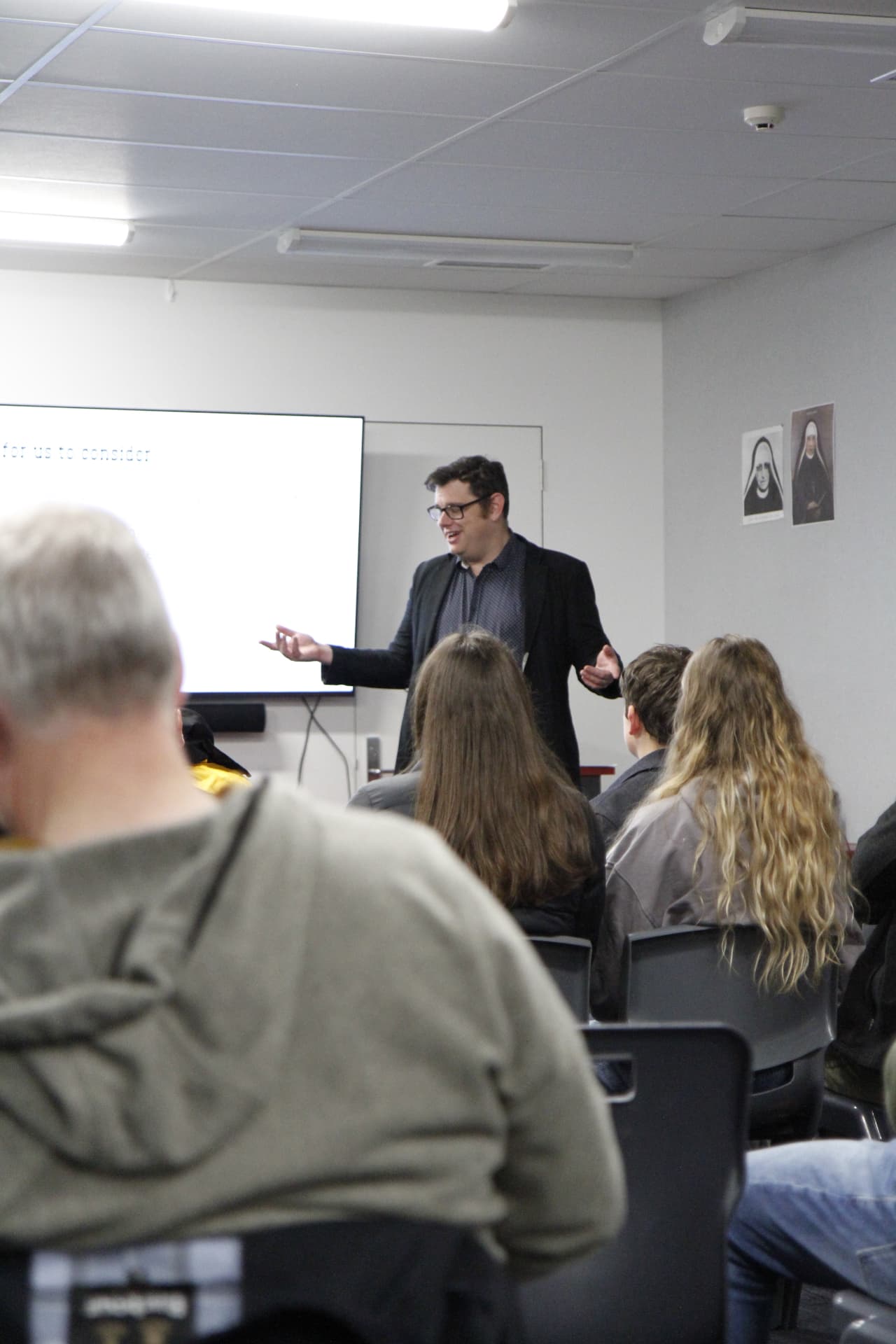 A tutor with glasses addressing the class during the course