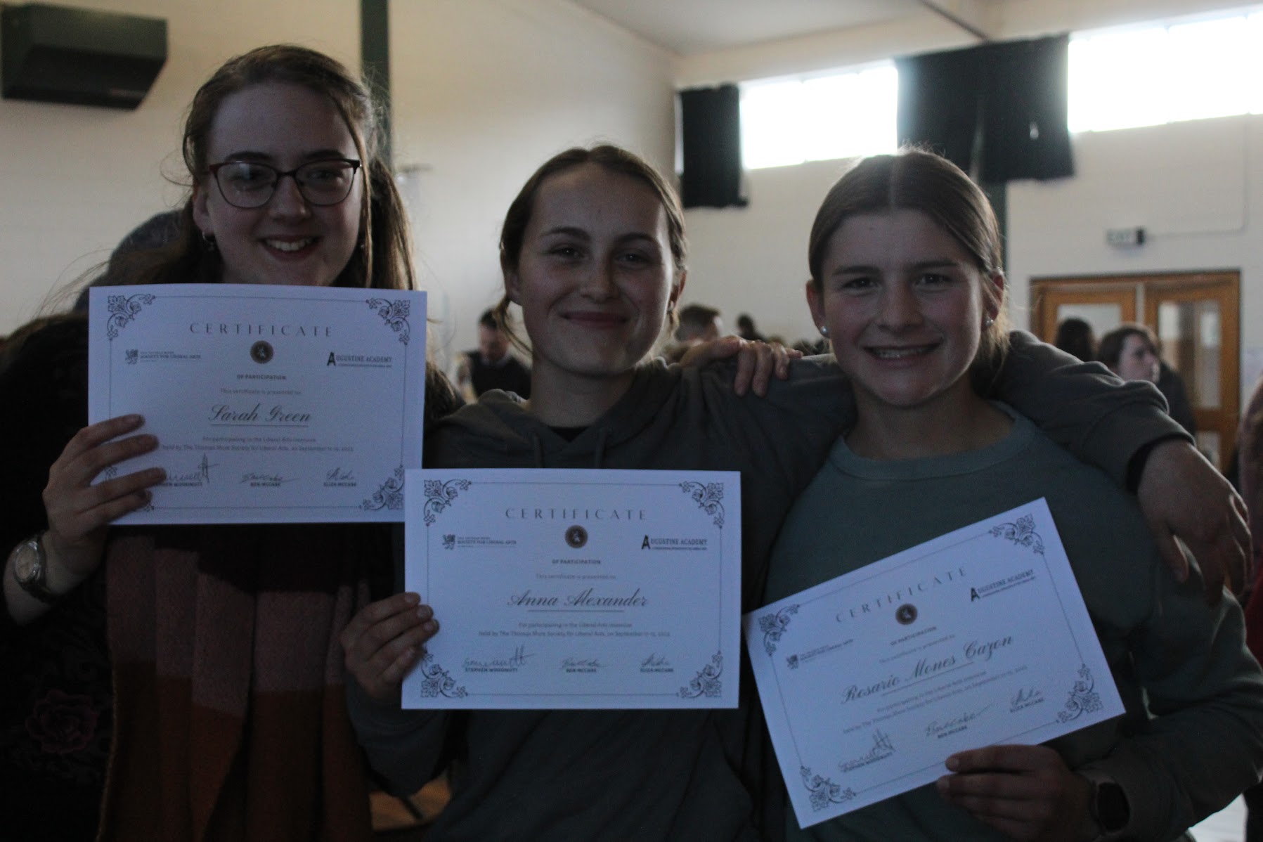 Three students holding their certificates of participation