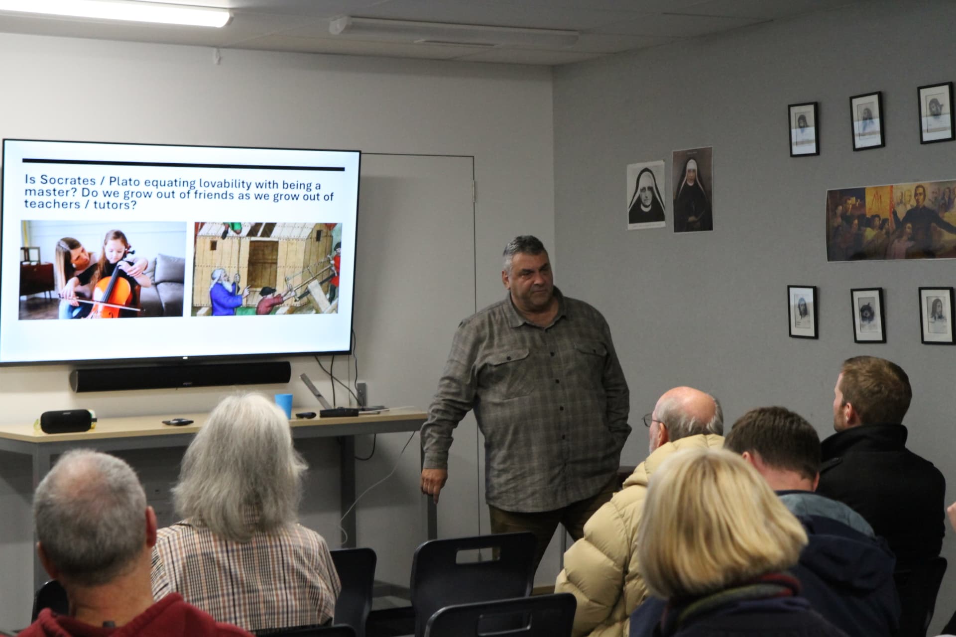 A tutor gesturing while presenting to the evening audience